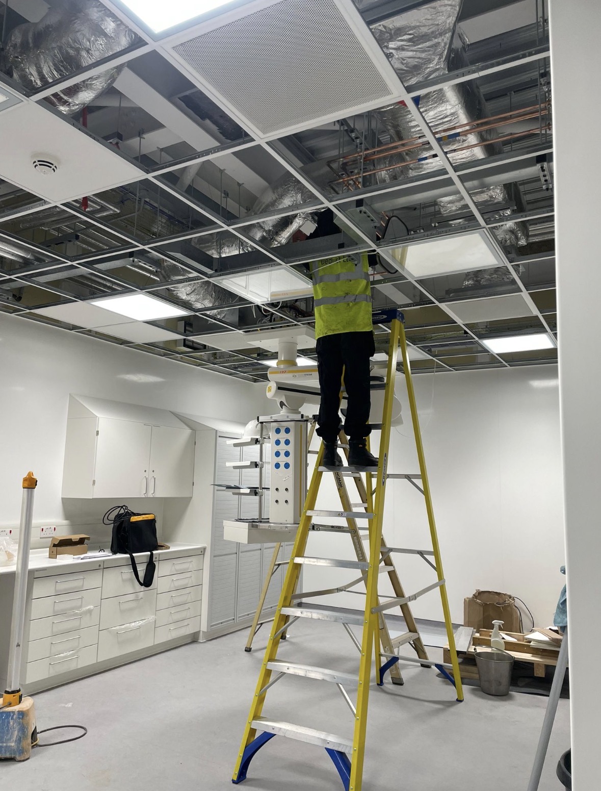 Deduct Ltd engineer carrying out hospital ventilation cleaning above a suspended ceiling in an NHS clinical area